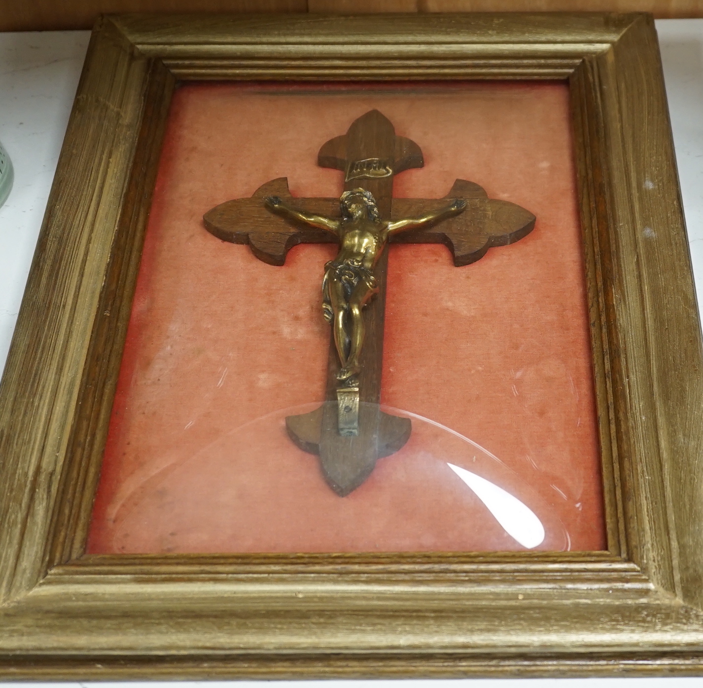 An oak and brass crucifix framed behind convex glass, overall 51cm x 37cm